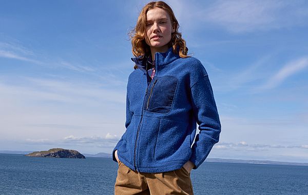 Drei Blautöne: Frau trägt blaue Jacke mit Meer und blauem Himmel im Hintergrund