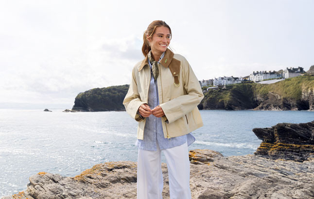 Frau vor Bucht in lässiger Windjacke