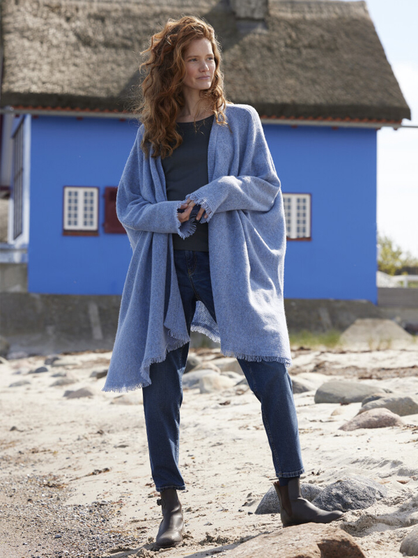 Strickcape mit blauem Haus am Strand in Heiligenhafen