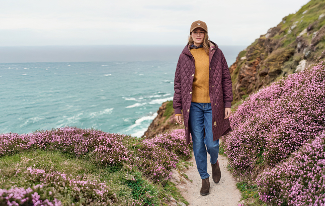 Frau auf Küstenwanderweg zwischen Heidekraut