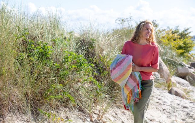 Frau mit buntem Plaid am Strand