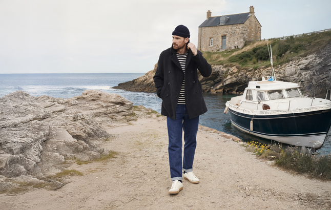 Mann in Caban-Jacke neben Motorboot