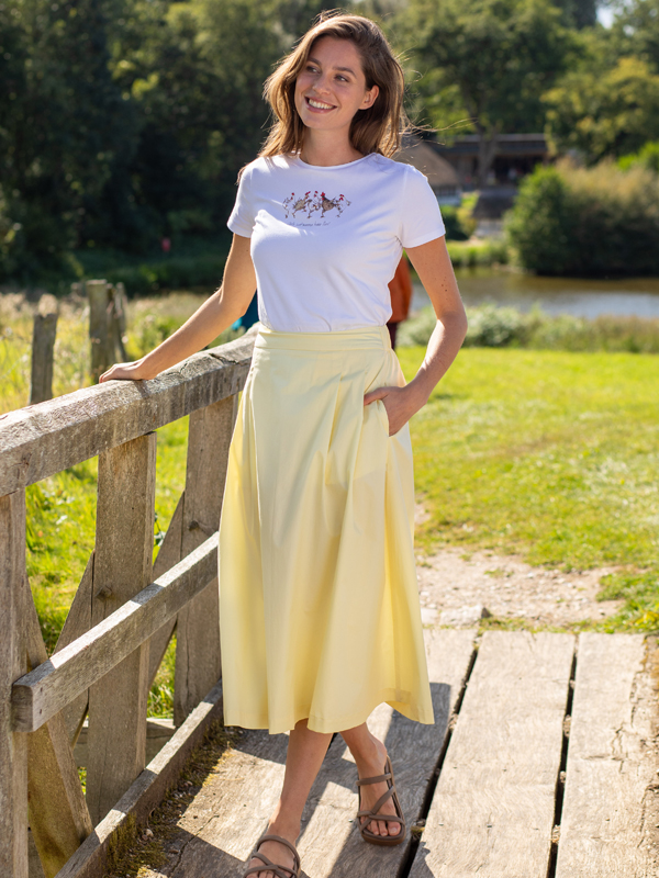Pastellgelber Rock mit weißem T-Shirt kombiniert