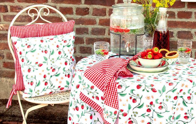Gemütliche Sitzecke mit Kissen und Tischdecke im Erdbeer-Dessin