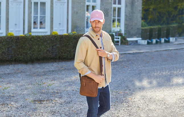 Mann mit Bag und Cap vor Landhaus