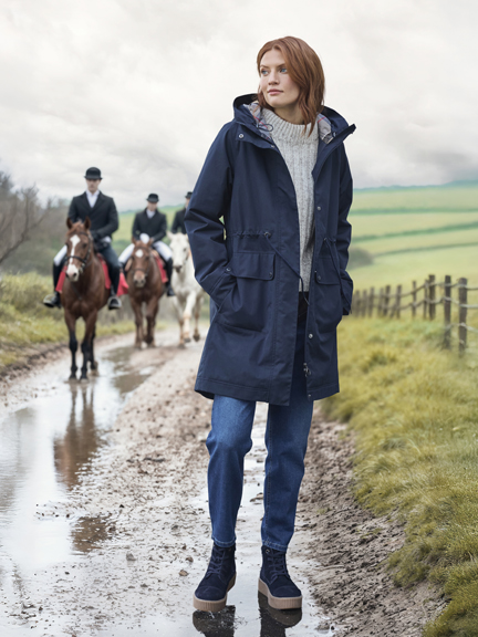 Frau an Reitweg im Parka